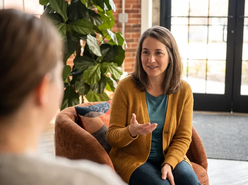 A HearthWell team member sitting in a warm brick room, talking with someone and answering their questions